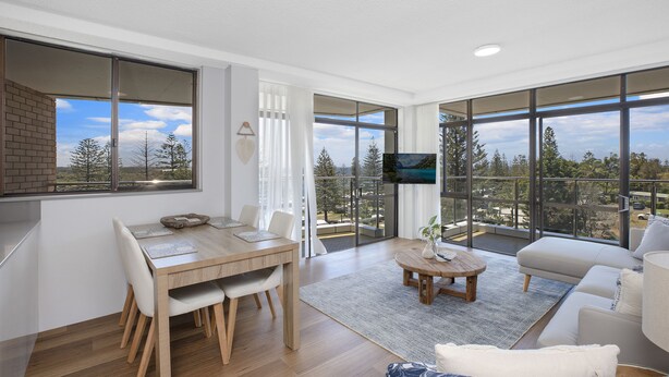 Una sala de estar moderna con comedor, ventanas amplias y un televisor de pantalla plana.