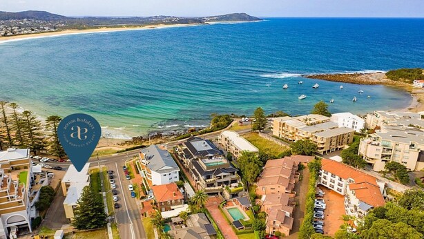Vista aérea de uma área costeira com edifícios, uma estrada e uma praia.