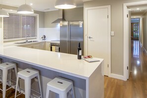 A modern kitchen with a central island, stainless steel appliances, and a pet-friendly sign. - Stylish 3BR Lake- front House + Kayaks (Encounter Bay)