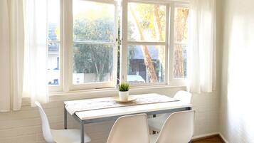 A dining area with a table, chairs, and a hanging light fixture.