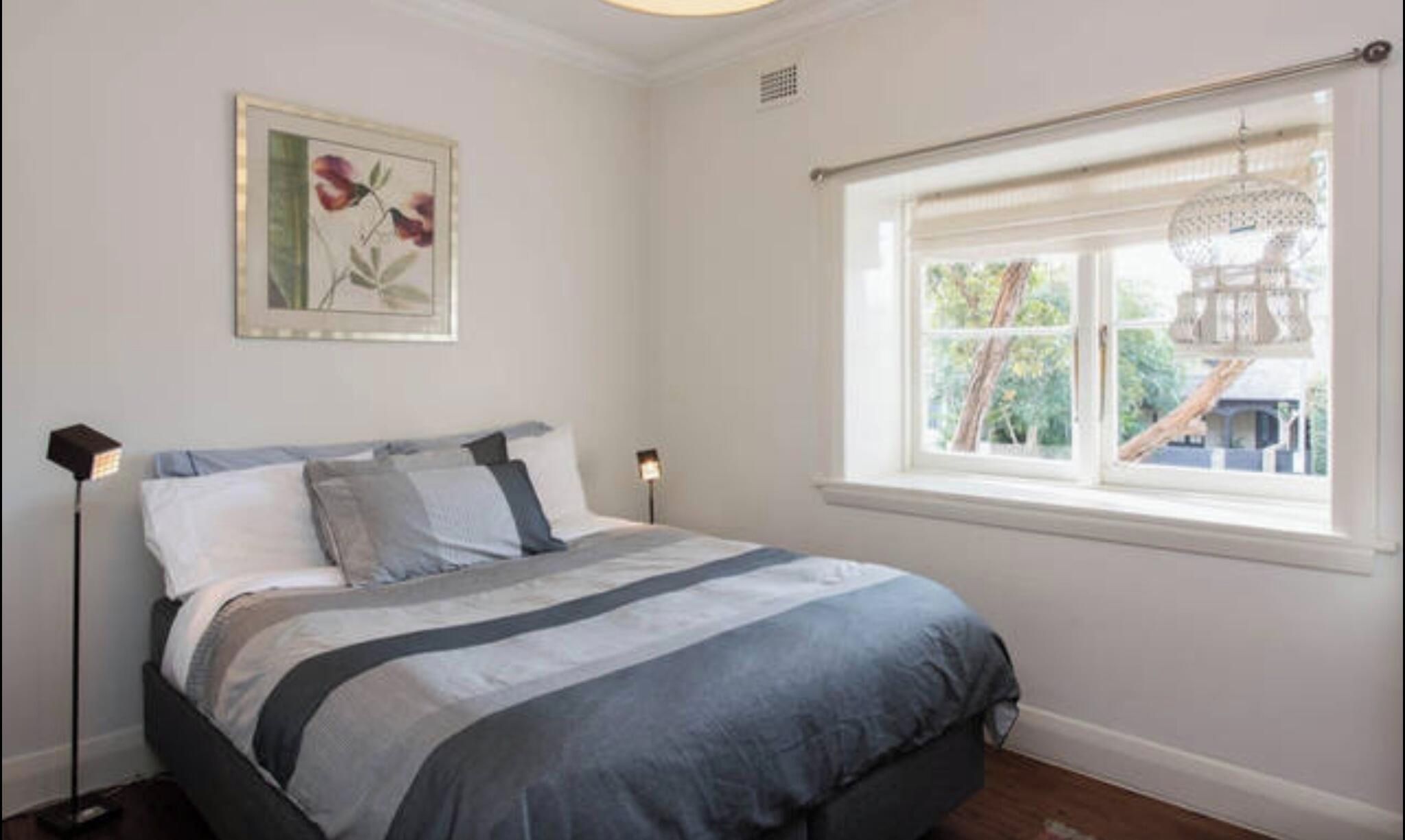 A bedroom with a bed, a window with a view, and a wall-mounted picture.