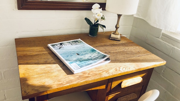 A wooden desk with a magazine, a lamp, and a potted orchid. - Free parking & 3 min walk to beach! (Bondi Beach)