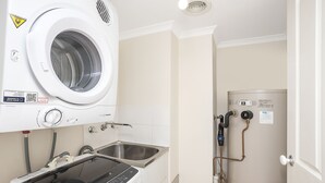 A laundry area with a front-loading washer and dryer, a sink, and a shower with visible plumbing.