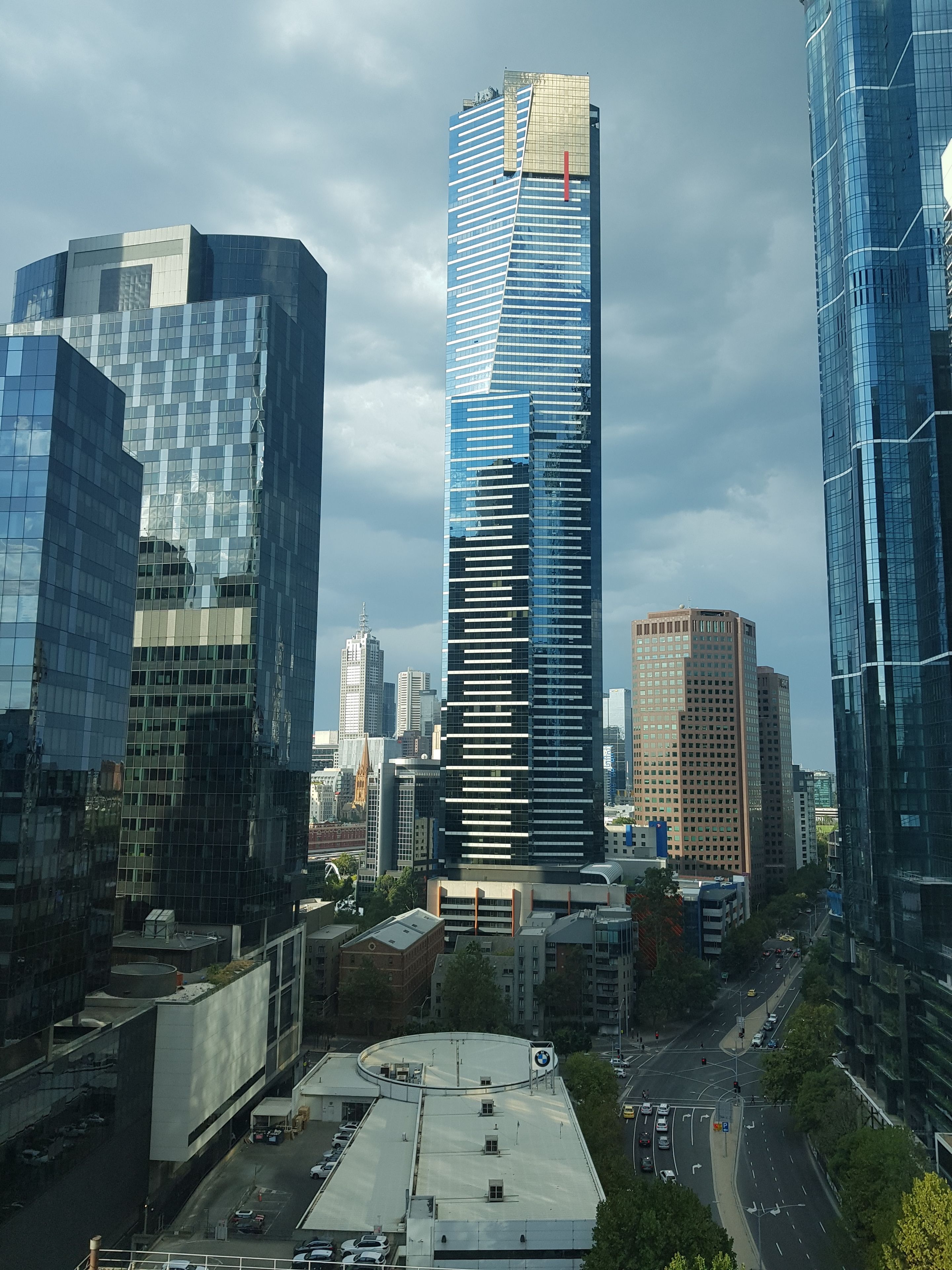 Een stadsgezicht met moderne hoge gebouwen, waaronder een opvallende wolkenkrabber met reflecterende glasramen.