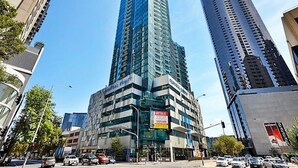 Un immeuble moderne de grande hauteur, doté d’une façade en verre, entouré d’autres bâtiments imposants.