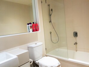 Ein Badezimmer mit Duschkabine, Toilette, Waschbecken und einem Spiegel über dem Waschbecken.