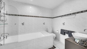 A modern bathroom with a glass shower enclosure, a bathtub, a toilet, and a sink. - Lagoon 206 Hamilton Island by HamoRent (Hamilton Island)