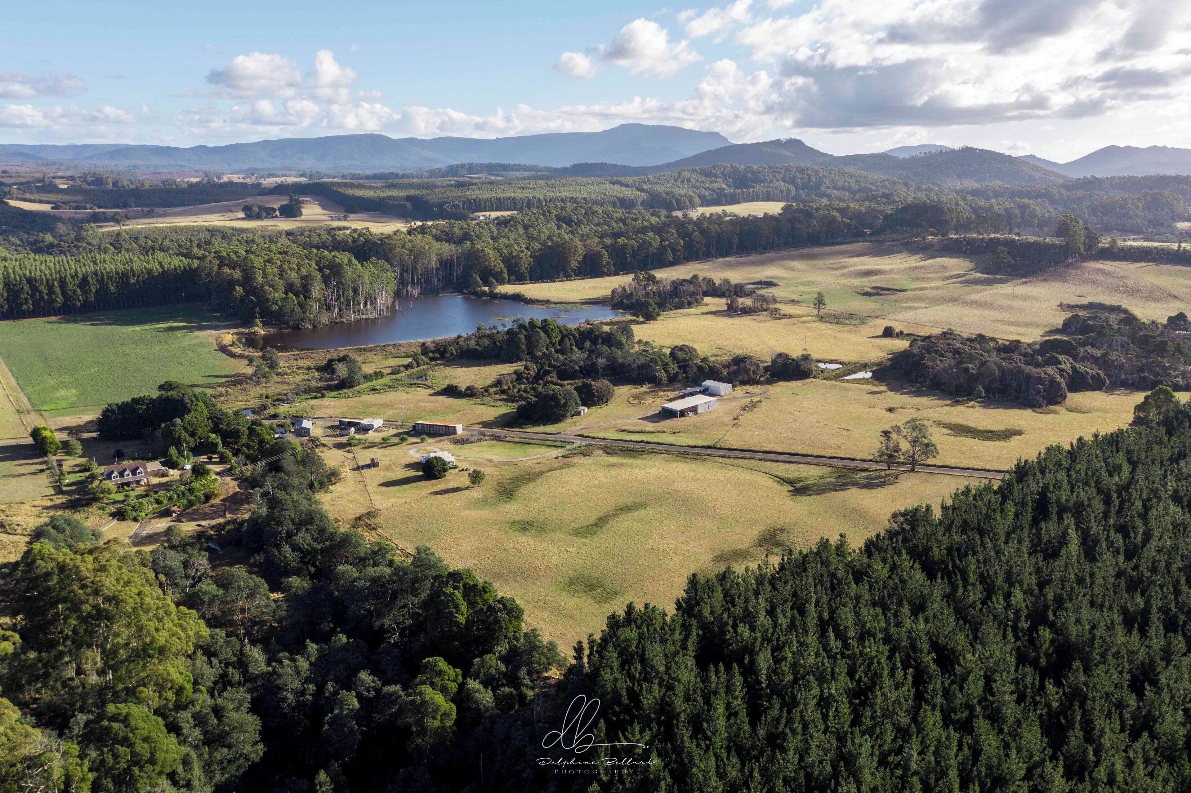 An aerial view of a rural landscape with a lake, fields, and scattered buildings.