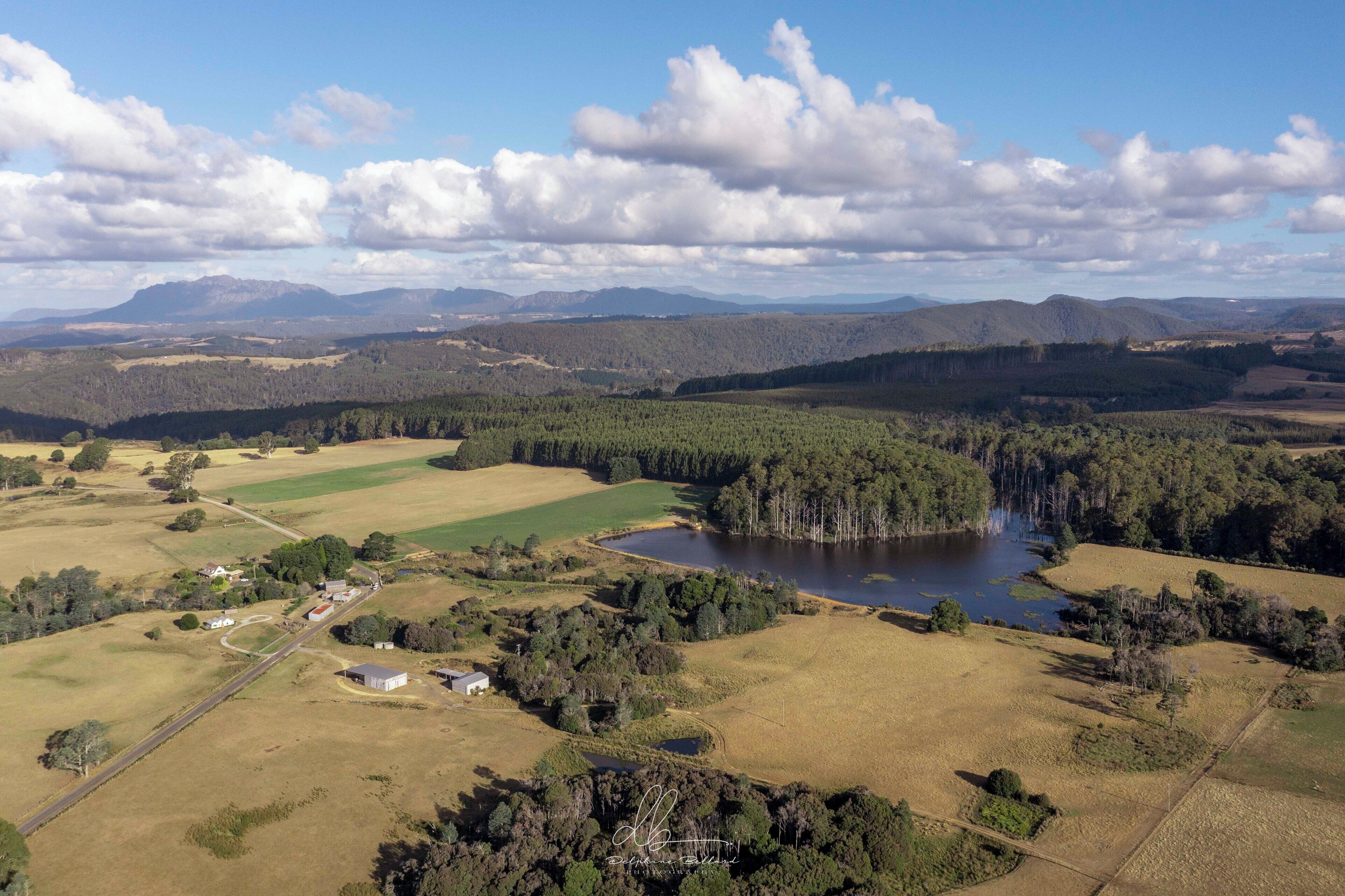 An aerial view of a rural landscape with a lake, fields, and scattered buildings.
