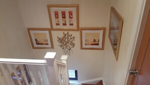 Ein Flur mit einer Treppe, einer Tür und drei gerahmten Bildern an der Wand.