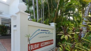 Señal de Port Douglas Apartments con un jardín tropical de fondo.