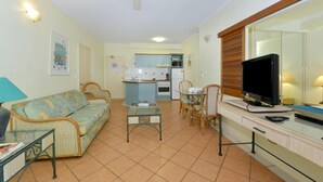 Un espacio habitable pequeño con kitchenette, un sofá, una mesa de comedor y un televisor.
