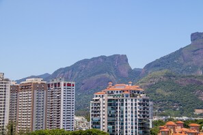 A high-rise building with multiple floors, surrounded by lush green hills and mountains.