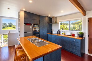 A modern kitchen with a wooden island, built-in appliances, and a view of greenery.