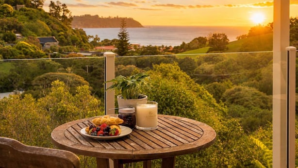Ein Tisch mit Essen, einer Kerze und einer Pflanze auf einem Balkon mit Blick auf eine malerische Landschaft bei Sonnenuntergang.
