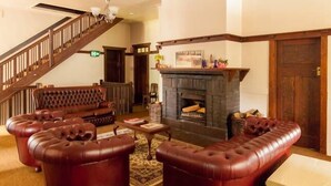 A traditional lobby with a fireplace, leather armchairs, a wooden staircase, and a reception desk. - Christmas 2026 Availability (Bundanoon)