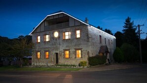 A two-story stone building with multiple windows, a front porch, and a chimney. - Christmas 2026 Availability (Bundanoon)
