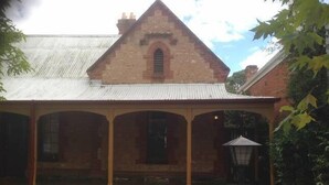 A brick building with a gabled roof and a covered porch. - Stanley Cottage 2 bedroom (North Adelaide)