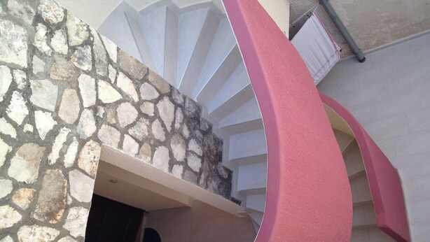 A spiral staircase with a stone wall and a pink accent wall. - Apartment Iva - Great Vacation in the Center of Fazana, Istra (Croatia) (Fazana)