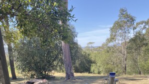 A picnic table with a glass top, surrounded by wooden benches. - Unique Rockhouse,  private jacuzzi, bush views (Rosebrook)
