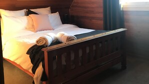 A wooden bed in a room with a sloped ceiling and a window. - Unique Rockhouse,  private jacuzzi, bush views (Rosebrook)