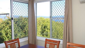 A room with a table and two chairs, a window with a view of trees and a body of water, and a curtain. - API Leisure & Lifestyle St Helens (St Helens)