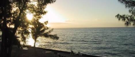 A beach with a view of the ocean and a sunset.