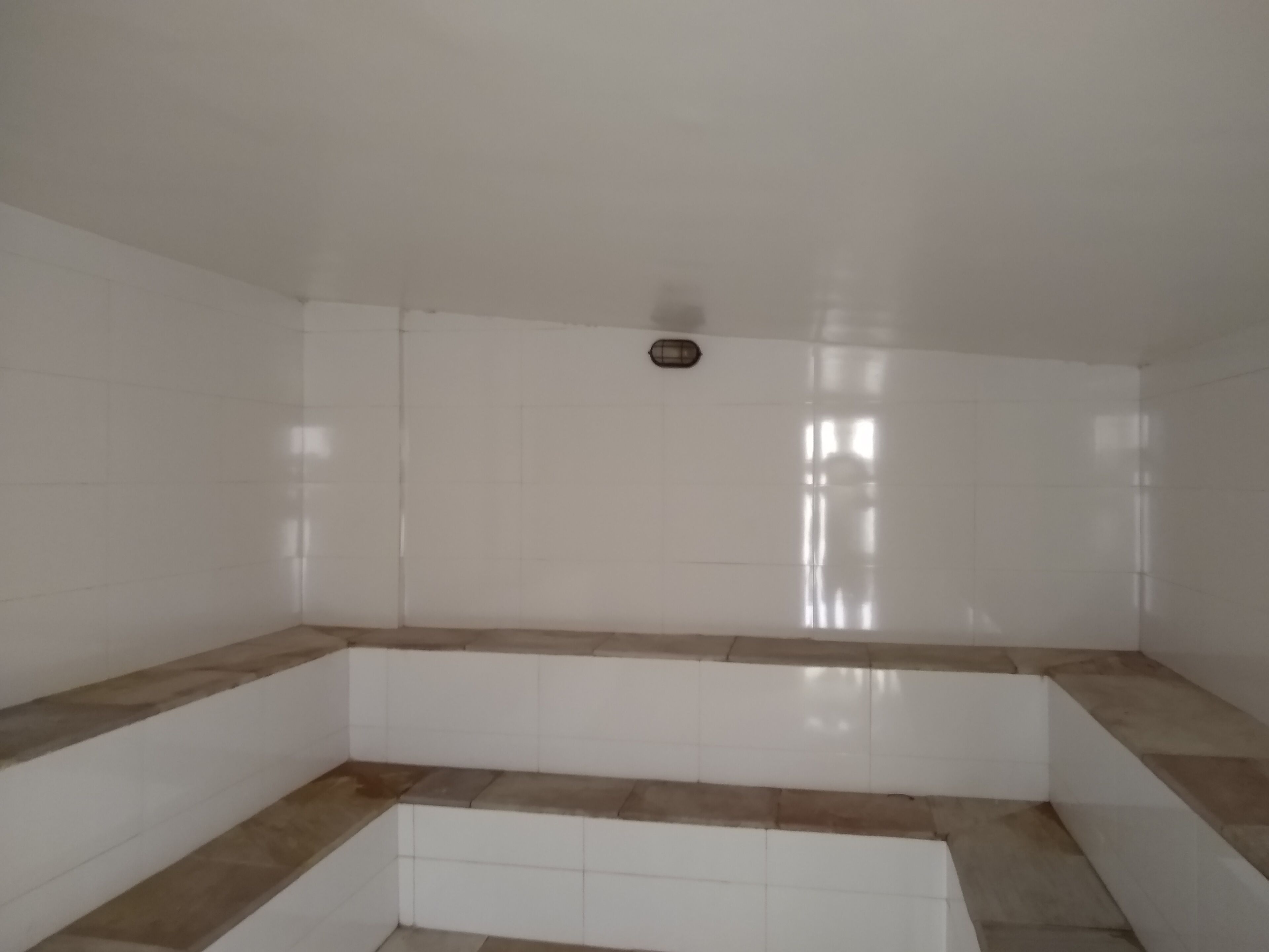 Een badkamer met witte betegelde wanden en een vloer van beige tegels.