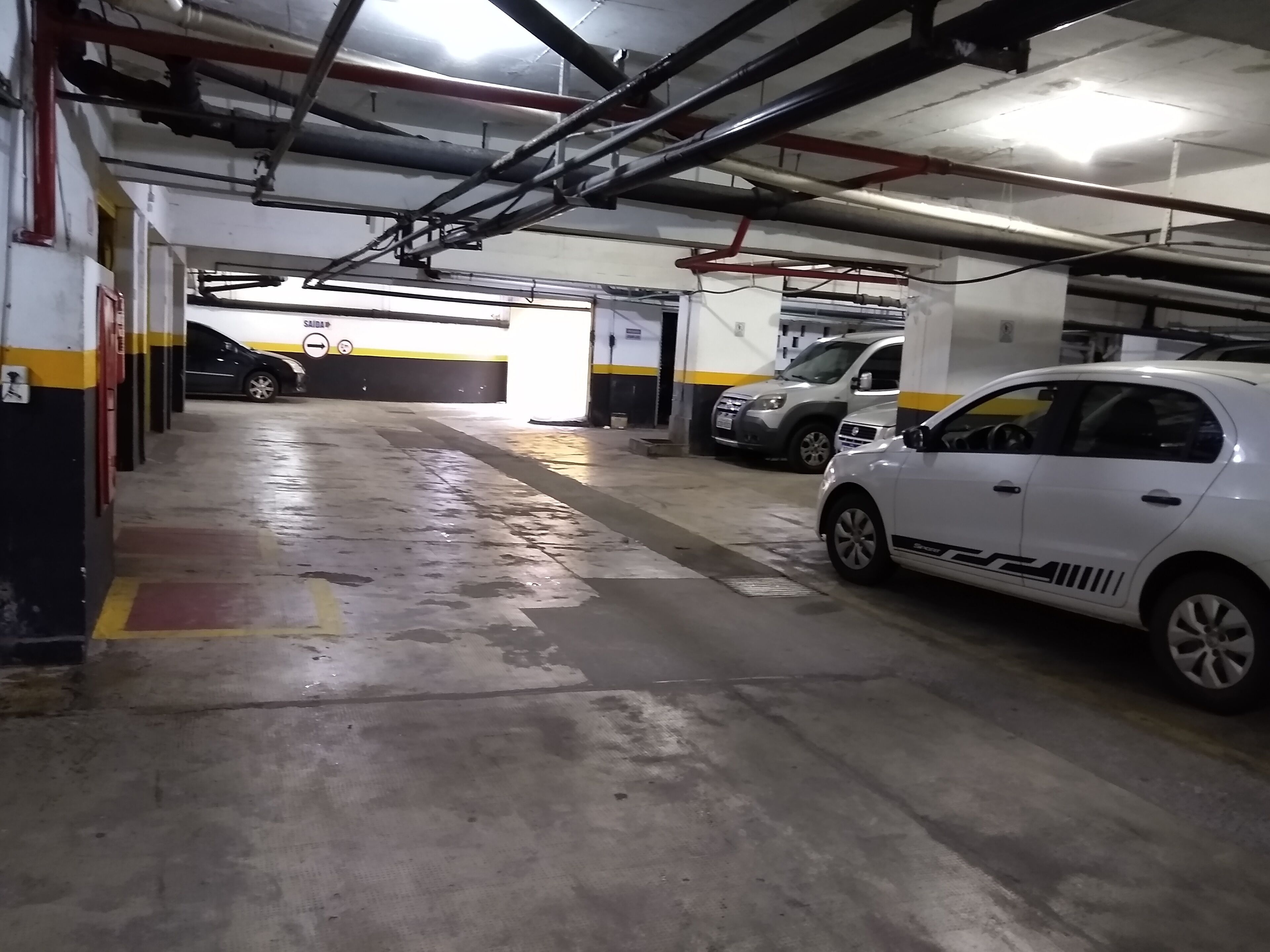 A multi-level parking garage with concrete floors and overhead pipes.