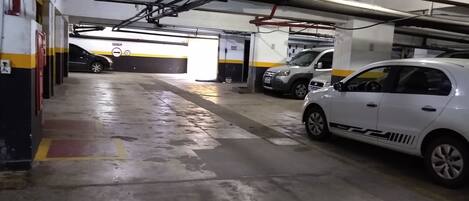 A multi-level parking garage with concrete floors and overhead pipes.