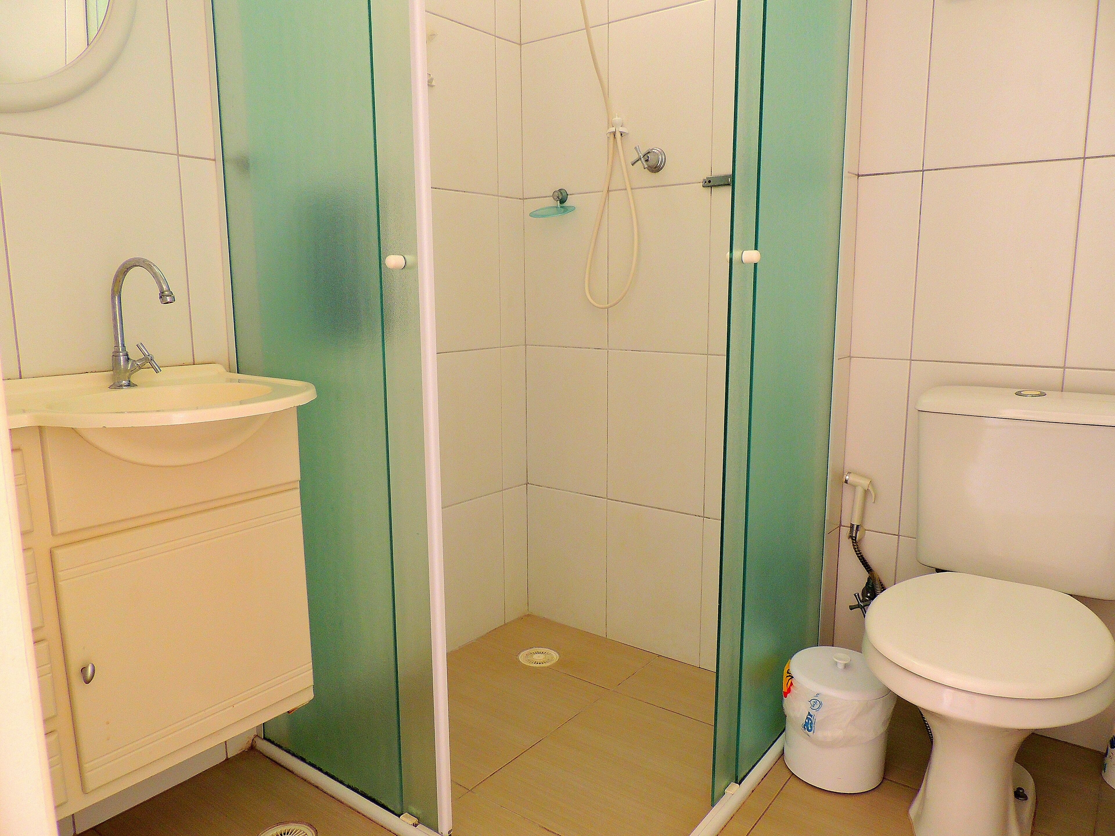 A bathroom with a sink, toilet, and shower enclosure.