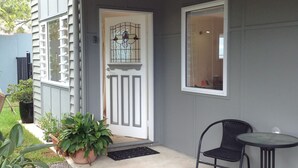 A house with a white door, a small porch, a potted plant, and a chair outside. - Lone Pine Retreat - Bright, airy spaces, full kitchen, kids & pets welcome! (Enoggera)
