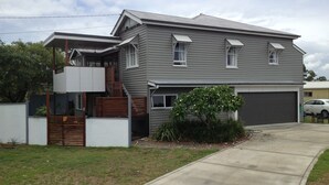 A two-story house with a garage, a covered porch, and a small garden area. - Lone Pine Retreat - Bright, airy spaces, full kitchen, kids & pets welcome! (Enoggera)