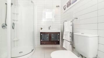 A modern bathroom with a glass-enclosed shower, a white toilet, and a vanity with a mirror.