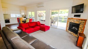 A spacious living room with a red sectional sofa, a fireplace, and a kitchen in the background. - BLUE HILLS RISE: Bright (Bright)
