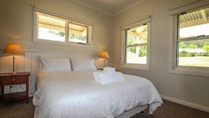 A neatly made bed with white linens and towels, two bedside lamps, and windows with blinds. - BLUE HILLS RISE: Bright (Bright)