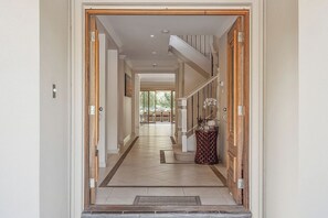 A hallway with a staircase leading to a landing, a patterned rug, and a small table with a lamp.