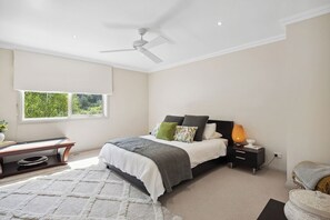 A bedroom with a bed, bedside table, lamp, and a window with blinds.