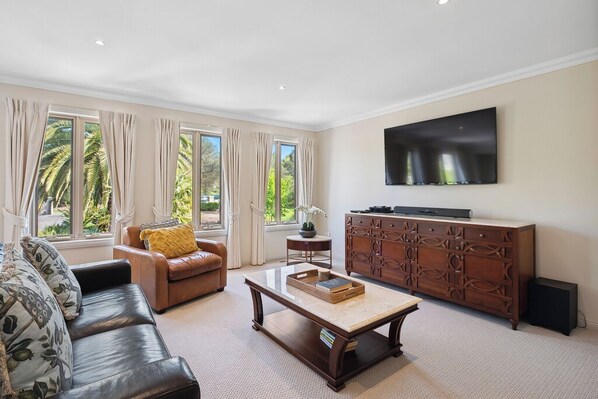 A living room with a sofa, armchair, coffee table, TV, and a cabinet.