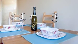 Ett matbord dukat med blommig porslin, en vinflaska och glas.