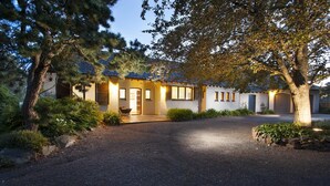 A two-story house with a driveway leading to the entrance, surrounded by trees and shrubs. - Boyanda At Ferny Creek - A wonderfully historic home with amazing views over the bays and sparkling lights. (Ferny Creek)