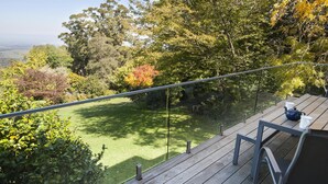 A balcony with a view of a green lawn and trees. - Boyanda At Ferny Creek - A wonderfully historic home with amazing views over the bays and sparkling lights. (Ferny Creek)