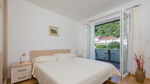 Un dormitorio con cama, mesita de noche y vistas a un balcón con mesa y sillas.