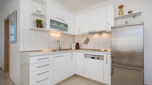 Una cocina moderna con armarios blancos, electrodomésticos de acero inoxidable y lavavajillas.