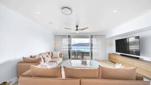 A modern living room with a sofa, a coffee table, and a TV. - The Elite F208 Hamilton Island by HamoRent (Hamilton Island)