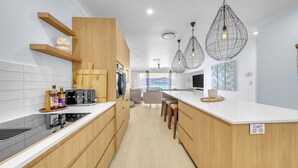 A modern kitchen with wooden cabinets, a built-in stove, and pendant lights. - The Elite F208 Hamilton Island by HamoRent (Hamilton Island)