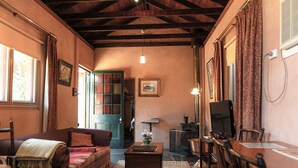 Un salon confortable avec un canapé, une table basse et un téléviseur. On y trouve également une bibliothèque et une porte qui donne sur une autre pièce.