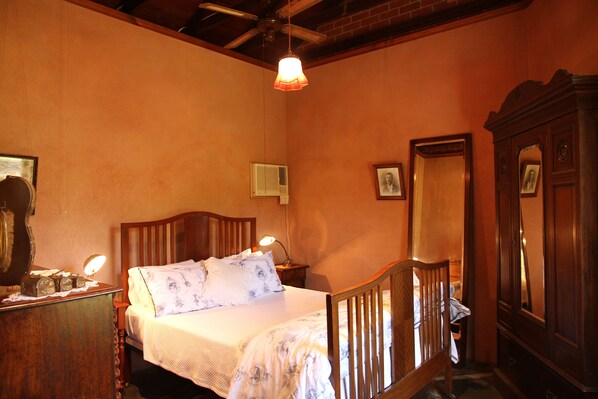 A bedroom with a wooden bed, bedside lamps, a dresser, and a mirror.