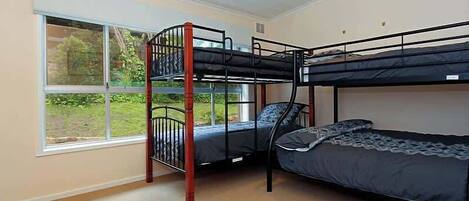 Ein Zimmer mit Etagenbetten, einem großen Fenster und Teppichboden.