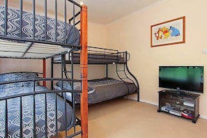 Ein Schlafraum mit Etagenbetten, einem Fernseher und einem gerahmten Bild an der Wand.